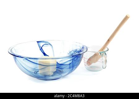 Eine blaue Glasmischschüssel mit Butter und einem leeren Messbecher isoliert auf weiß Stockfoto
