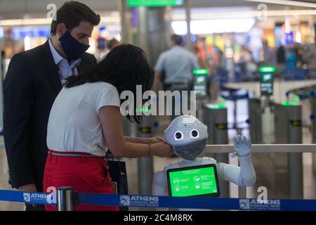 Athen, Griechenland. Juni 2020. Mitarbeiter des Athener Flughafens legen eine Gesichtsmaske auf einen Pepper Roboter in Athen, Griechenland, 26. Juni 2020. DAZU: 'Feature: Athens int'l Airport rekrutiert Roboter, um Reisende über COVID-19-Maßnahmen zu informieren' Credit: Marios Lolos/Xinhua/Alamy Live News Stockfoto