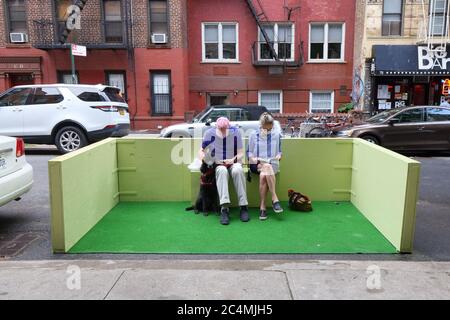New York, NY, 27. Juni 2020. Zwei Personen und ein Hund sitzen in einem Parklet im East Village Viertel von Manhattan. Parklets sind Bürgersteige Erweiterungen auf einer Parkspur einer Straße oder Straße, um öffentliche Raum zu erhöhen. Im Rahmen der Phase 2 der Neueröffnung in New York City, die es Restaurants ermöglicht, Kunden zu bedienen, werden Parklets für gesellschaftlich distanzierte Mahlzeiten im Freien genutzt. Stockfoto