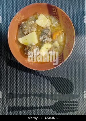 Vertikale Aufnahme von Suppe von Fleischbällchen mit Kartoffeln und Squash In einer Schüssel auf einem Tischset Stockfoto