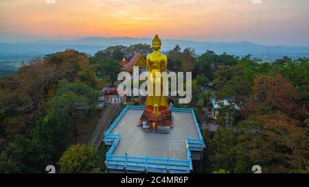 Luftaufnahmen der golden Big Buddha Statue stehend auf einem Hügel im Sonnenuntergang am Wat Phra That Jom Wae in Chiang Rai Thailand Stockfoto