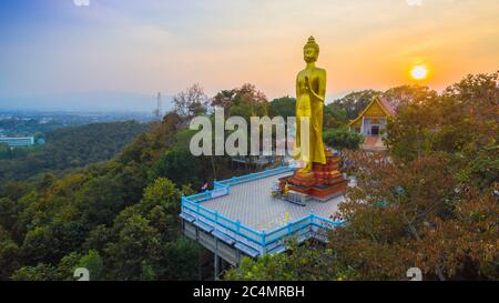 Luftaufnahmen der golden Big Buddha Statue stehend auf einem Hügel im Sonnenuntergang am Wat Phra That Jom Wae in Chiang Rai Thailand Stockfoto