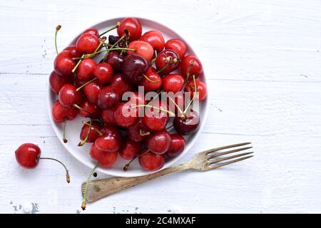 Frische saftige rote Kirschen isoliert auf weißem Hintergrund / rote frische Kirschen süße Kirschen Beeren auf weißem Holz Hintergrund Stockfoto