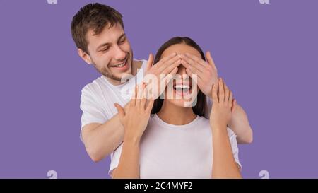 Mann, der die Augen seiner Frau von hinten bedeckt Stockfoto