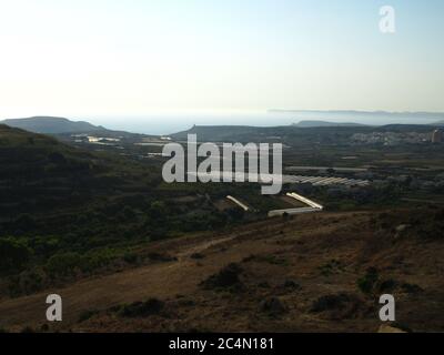 MGARR, MALTA - 19. Jul 2014: Landschaft des Mgarr-Tals, Teil der Landschaft und ländlichen Gegend von Malta mit mehreren Gewächshäusern, Hügeln, Meer und t Stockfoto