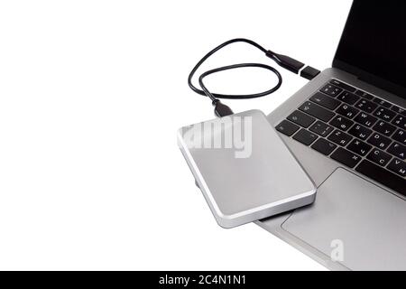 Tragbare silberfarbene festplatte, die über usb-Kabel mit einem Laptop verbunden ist. Isoliert auf Weiß, Kopierbereich. Datenspeicherung oder System-Backup-Konzept. Stockfoto