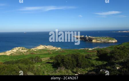 ST PAUL'S BAY, MALTA - 10. Feb 2014: St Paul's Islands, oder Selmunet, vor der Küste von Malta, mit einer Statue von St Paul auf der Spitze, und Fischfarmen in der Nähe. Stockfoto