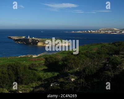 ST PAUL'S BAY, MALTA - 10. Feb 2014: St Paul's Islands, oder Selmunet, vor der Küste von Malta, mit einer Statue von St Paul auf der Spitze, und Fischfarmen in der Nähe. Stockfoto