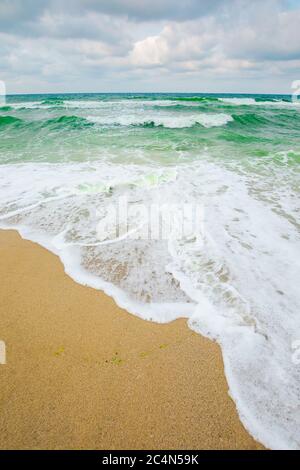 Flut an einem bewölkten Abend. Wellen knallenden Sandstrand Stockfoto