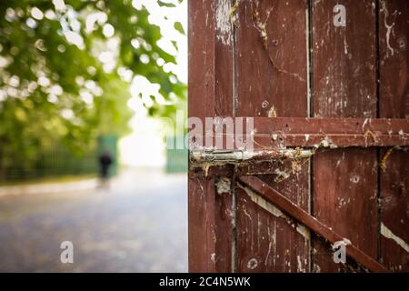 Bild mit geringer Schärfentiefe (selektiver Fokus) mit einem alten und ungenutzten Metallriegel auf einem Holztor. Stockfoto