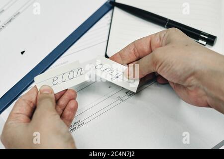 Mann hält ein zerrissenes Stückiskbudgeteconomiccostdown von Papier mit dem Wort „Economy“ für die IT Stockfoto