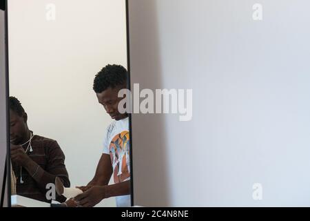 Politische Flüchtlinge und afrikanische Einwanderer arbeiten an der Schneiderei der gemeinnützigen Vereinigung im Süden Italiens, Neapel. Stockfoto