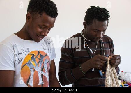 Politische Flüchtlinge und afrikanische Einwanderer arbeiten an der Schneiderei der gemeinnützigen Vereinigung im Süden Italiens, Neapel. Stockfoto