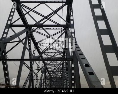 Metallkonstruktion der Eisenbahnbrücke mit dem aufsteigenden Mittelteil für die Durchfahrt von Schiffen. Blick von unten vom Fenster des Autos. Architektur, Designelemente Stockfoto