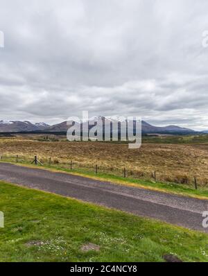 Schöne Landschaft mit einer Straße und hohen Bergen bedeckt Schnee schimmert unter dem wolkigen Himmel Stockfoto