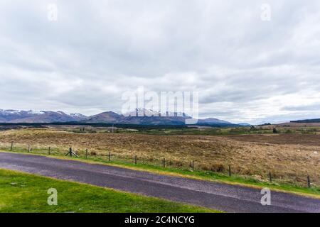Schöne Landschaft mit einer Straße und hohen Bergen bedeckt Schnee schimmert unter dem wolkigen Himmel Stockfoto