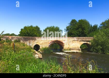 Eine Dame, die auf der Brücke über den Fluss Great Ouse, Harrold, Bedfordshire, Großbritannien, radelt Stockfoto