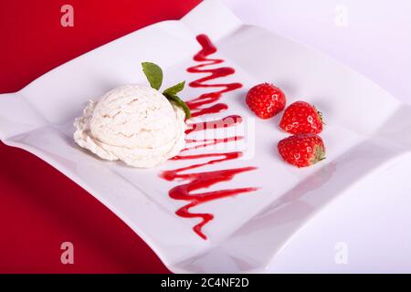 Ausgefallenen Dessert mit Erdbeeren, Vanilleeis und Himbeersauce Stockfoto