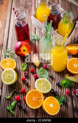 Auswahl an Säften und Limonaden mit Früchten und Kräutern auf Holztisch Stockfoto