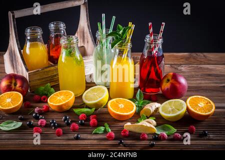 Auswahl an Säften und Limonaden mit Früchten und Kräutern auf Holztisch Stockfoto