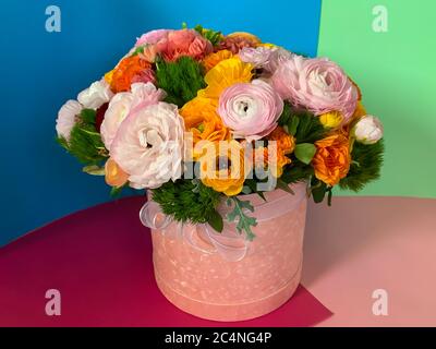 Leuchtend bunte rosa gelb orange persisch asiatische Butterblume asiatischer Blumenstrauß in runden Box Stockfoto