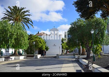 Yaiza, Spanien - 16. Januar 2012: Unbekannte Menschen auf dem Hauptplatz - Plaza de los Remedios - mit der Kirche Nuestra de los Remedios in dem kleinen Dorf Stockfoto