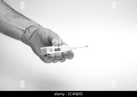 Hand in Schutzhandschuh hält elektronisches Thermometer, Spritze, chirurgische Maske, Pillen und Grippe-Impfstoff auf blau. Chinesisches Wuhan-Coronavirus COVID-19-Virus Stockfoto