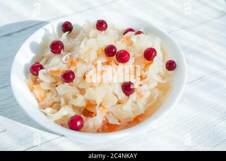 Sauerkraut mit Preiselbeeren in einer weißen Tasse, Nahaufnahme. Probiotika Lebensmittelkonzept. Selektiver Fokus, Kopierbereich für Text Stockfoto