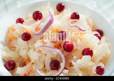 Sauerkraut mit Preiselbeeren und Zwiebeln in einer weißen Tasse, Nahaufnahme. Probiotika Lebensmittelkonzept. Selektiver Fokus, Kopierbereich für Text Stockfoto