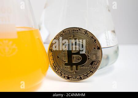 Nahaufnahme einer BTC-Bitcoin-Münze, umgeben von Chemikalien und Laborglas. Die Wissenschaft der Kryptowährung. Stockfoto