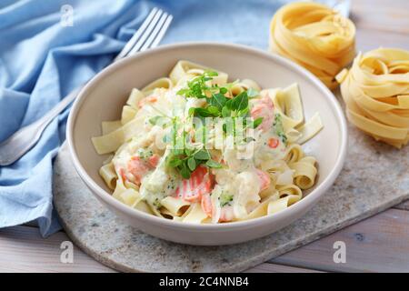 Schüssel kalorienarme Fettuccine Alfredo mit Karotte und Gemüse garnieren mit frischen Basilikumblättern. Vorbereitung für das Mittagessen Gericht mit leckeren cremigen Sauce A Stockfoto