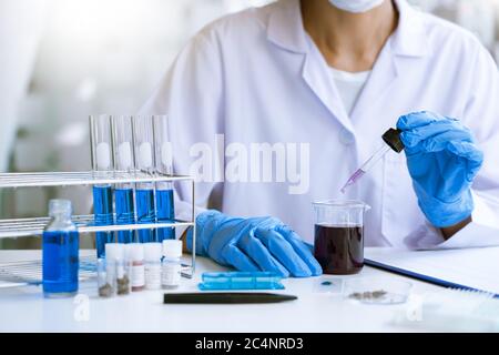 Wissenschaftler, die im Labor im weißen Labormantel recherchieren, Handschuhe analysieren, Reagenzgläser Probe betrachten, Biotechnologiekonzept. Stockfoto