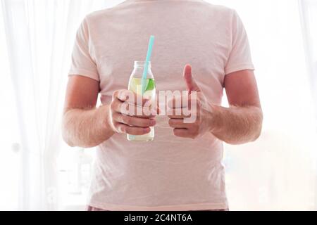 Man trinkt Limonade durch einen Strohhalm aus der Glasflasche. Abgeschnitten. Stockfoto