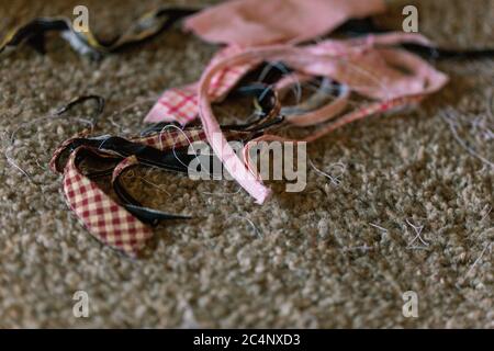 Stoffreste auf dem Boden schwarz auburn gingham rosa gingham weißen Fäden Stockfoto