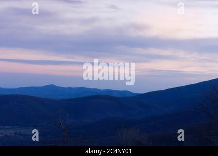 Die Sonne untergeht hinter den Blue Ridge Mountains von Virginia, was zu pastellfarbenen Himmel und Nebel in den Tälern führt. Stockfoto