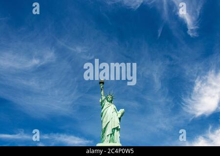 Weitwinkel-Ansicht der Freiheitsstatue gegen einen wolkigen blauen Himmel, New York City. Stockfoto