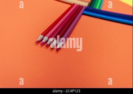 Farbstifte auf rot-orangem Hintergrund.Nahaufnahme. Stockfoto