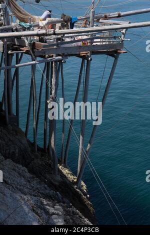 Trabucco ist ein Bau von Holzpfosten in Felsen in Vieste, Italien entlang der Adria. Ein Fischer arbeitet auf der Plattform des Trabucco Stockfoto