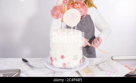 Einfügen von großen Lutscher mit Schneeflocken in den hohen Weiße, runde Kuchen als Dekoration. Stockfoto