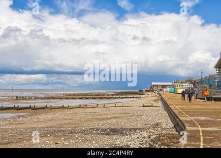 Eine einsame Gruppe von Menschen, die an einem sonnigen Tag während der Sperre in Hunstanton, Norfolk, England, England, an einem sonst menschenleeren Abschlussball entlang gehen Stockfoto