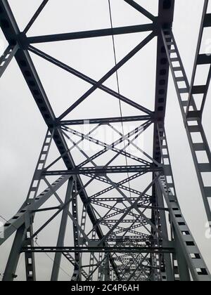 Metallkonstruktion der Eisenbahnbrücke mit dem aufsteigenden Mittelteil für die Durchfahrt von Schiffen. Blick von unten vom Fenster des Autos. Architektur, Designelemente Stockfoto