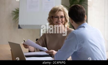 Lächelnde reife Geschäftsfrau diskutiert Startup-Ideen mit Geschäftspartner Stockfoto