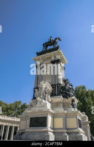 Madrid, Comunidad de Madrid, Spanien, Europa.. El Retiro Park (Parque del Retiro). Statue des Königs Alfonso XII, die Teil einer Gruppe ist, die aus einer großen Marmorkolonnade mit zahlreichen Skulpturen besteht, die die Bronzestatue des Königs umgeben. Das Denkmal, wurde am 6. Juni 1922 eingeweiht und vom Architekten José Grases Riera erbaut. An der Basis links die Freiheitsstatue, Kalkstein Skulpturengruppe von Aniceto Marinas (1866-1953). Rechts: Peace, Bronze-Skulpturengruppe von Miquel Blay (1866-1936). Stockfoto