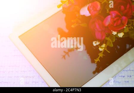 Ein PC-Tablet mit einem Blumenstrauß auf dem Tisch. Alles gute zum Tag des Lehrers. Schulungsraum. Draufsicht. Beginn des Schuljahres. Zurück zur Schule Konzept Stockfoto