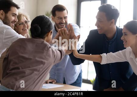 Glückliche, vielfältige Mitarbeiter treffen sich und feiern Teamerfolg beim Meeting Stockfoto