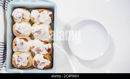 Flach liegend. Glasur frisch gebackene Zimtschnecken in einer blauen Backform. Stockfoto