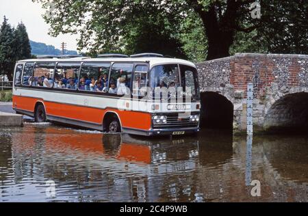 Coach, als Schulbus, durch das Wasser der furt in Eynsford, Kent, England, viel zu der Aufregung der Kinder an Bord Stockfoto