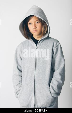 Elf Jahre alter Junge mit Kapuzenpullover vor weißem Hintergrund Stockfoto