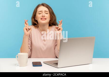 Frau Angestellte sitzt am Arbeitsplatz in Erwartung einer angenehmen Geschäftsveranstaltung, kreuzt ihre Finger und wünscht viel Glück, träumen von Beförderung. Stockfoto