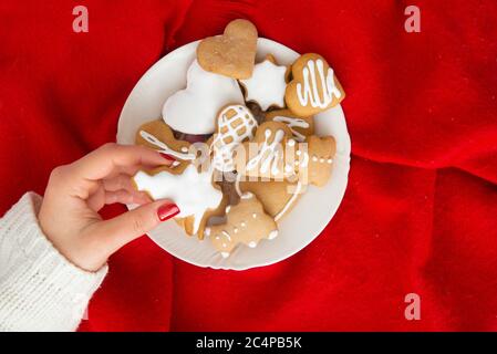 Glasierte Weihnachts-Kekse anders geformt. Feuerbaum Lebkuchen, herzförmige Lebkuchen und Teddybär Lebkuchen mit rotem Hintergrund. Stockfoto